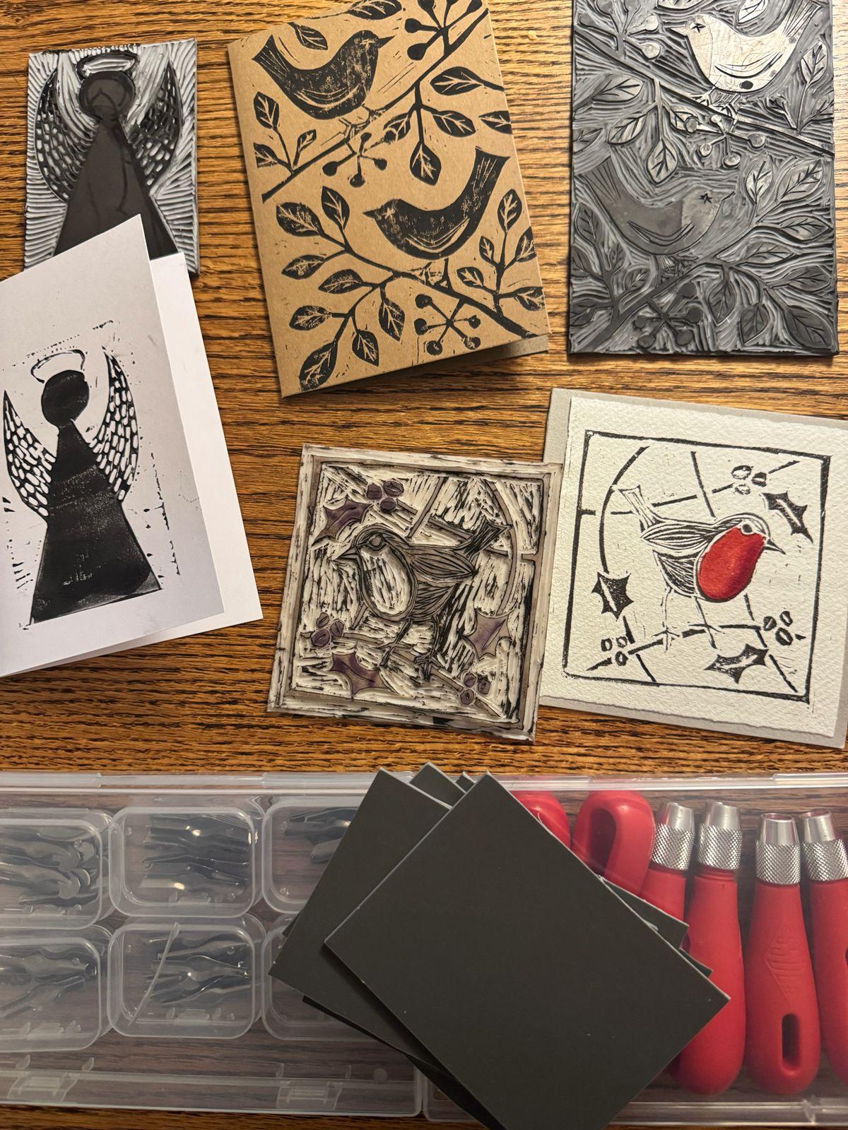 Hand printed Christmas cards with birds and an angel beside carved lino blocks and tools